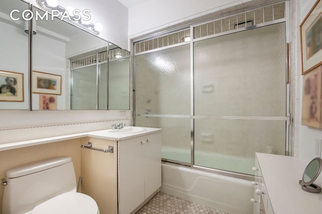 full bathroom featuring vanity, tile patterned floors, shower / bath combination with glass door, and toilet