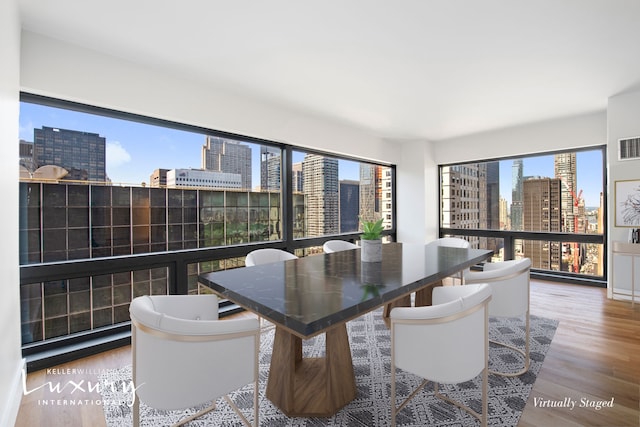 dining area with a city view, visible vents, and wood finished floors