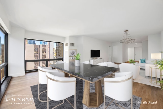 dining space with wood finished floors, visible vents, and baseboards