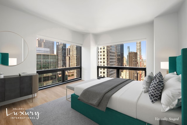 bedroom with a view of city and wood finished floors