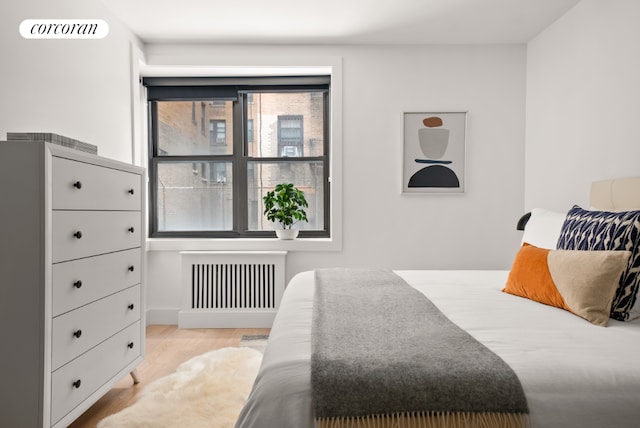 bedroom with radiator and light hardwood / wood-style floors