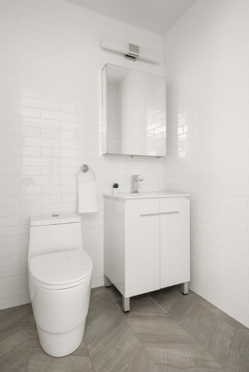 bathroom featuring vanity, tile walls, tile patterned floors, and toilet