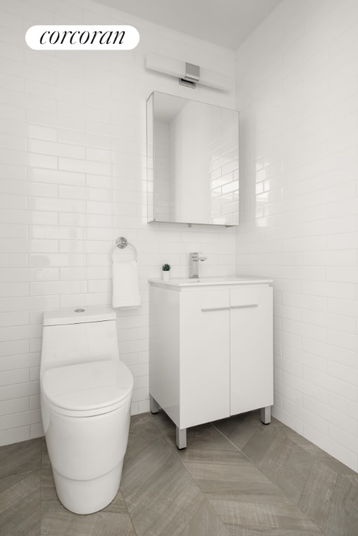 bathroom with vanity, tile patterned floors, toilet, and tile walls