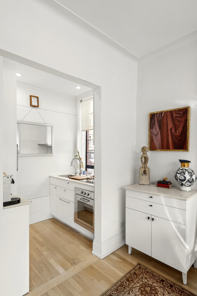 bar area featuring oven, light wood-style flooring, a sink, and recessed lighting