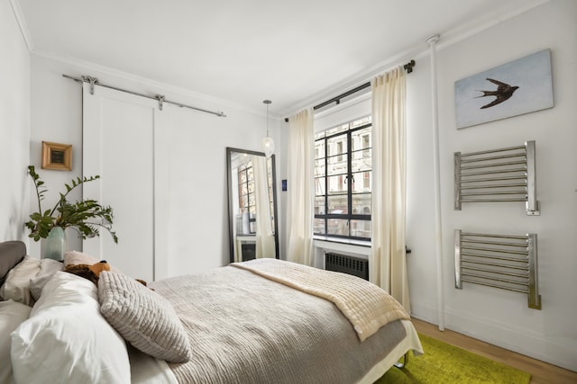 bedroom with radiator, baseboards, ornamental molding, and wood finished floors