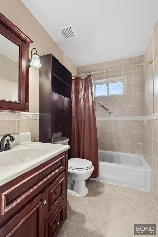 bathroom with shower / bath combo, visible vents, tile patterned floors, vanity, and tile walls