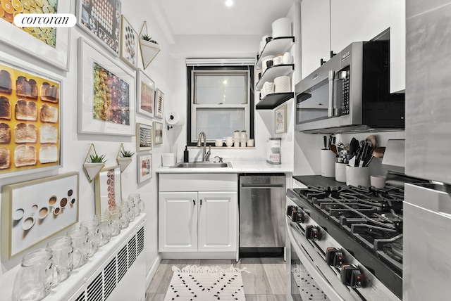 kitchen with white cabinetry, sink, radiator heating unit, and appliances with stainless steel finishes