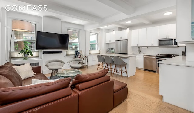 living area with light wood finished floors, beamed ceiling, and recessed lighting