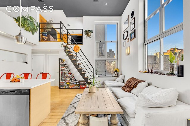 living room featuring stairs, a high ceiling, and light wood-style floors