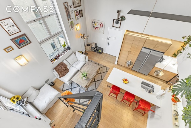 living area with light wood finished floors and a towering ceiling