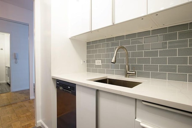 kitchen featuring sink, dishwasher, white cabinetry, parquet floors, and decorative backsplash