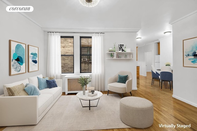 living room featuring visible vents, baseboards, radiator heating unit, ornamental molding, and wood finished floors