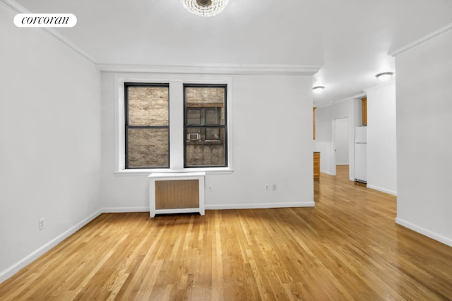 unfurnished room featuring crown molding, radiator heating unit, and light hardwood / wood-style floors