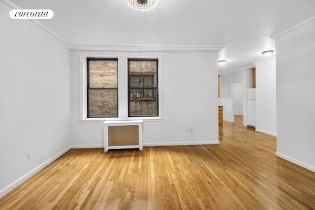 unfurnished room featuring ornamental molding, light wood-style flooring, visible vents, and radiator