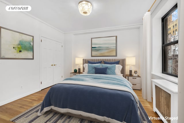 bedroom featuring visible vents, ornamental molding, wood finished floors, radiator heating unit, and baseboards