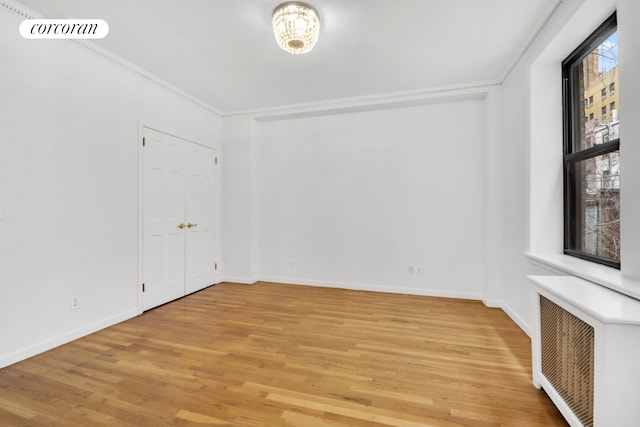 empty room with light wood-style flooring, baseboards, and ornamental molding