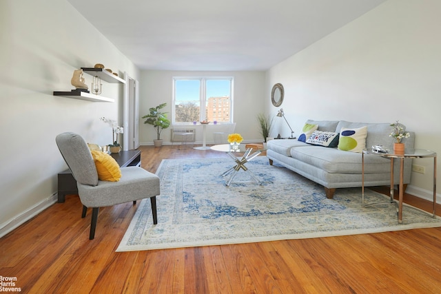 living area with an AC wall unit, wood finished floors, and baseboards