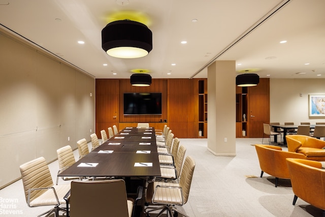 carpeted dining area featuring wooden walls