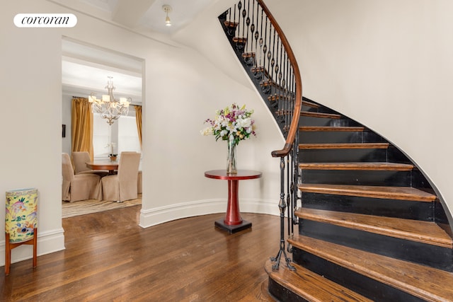 stairs featuring a chandelier, wood finished floors, visible vents, and baseboards