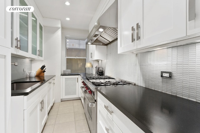 kitchen featuring glass insert cabinets, dark countertops, stainless steel range, and ventilation hood