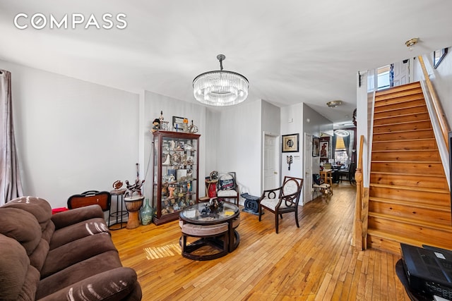 living area with stairs, an inviting chandelier, and light wood-style floors