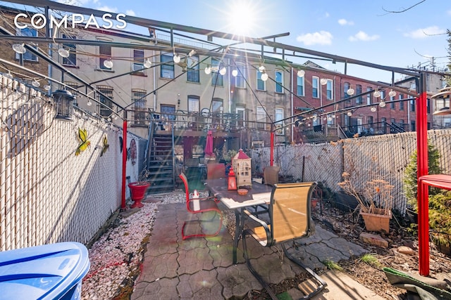 view of patio / terrace with outdoor dining area, fence, and stairway