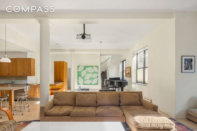 living area with light wood-style floors, decorative columns, and stairway