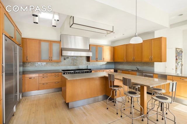 kitchen with glass insert cabinets, a center island, appliances with stainless steel finishes, and ventilation hood