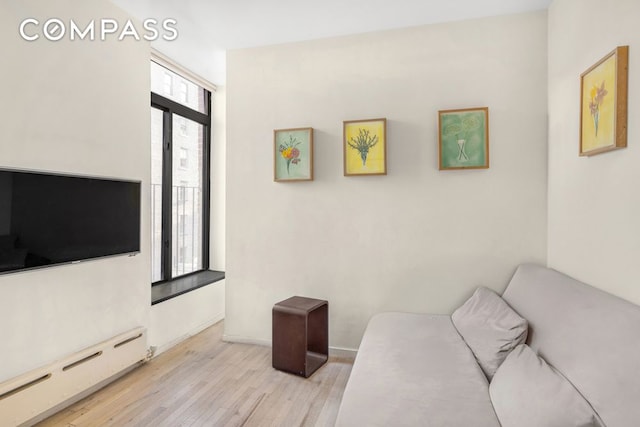 living area featuring a baseboard heating unit and light wood-style flooring