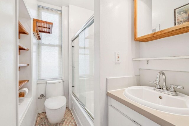 full bathroom featuring bath / shower combo with glass door, vanity, toilet, and tile patterned floors