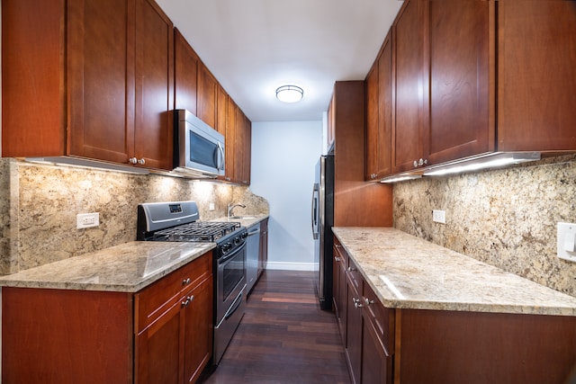 kitchen featuring light stone counters, stainless steel appliances, dark wood-style flooring, baseboards, and decorative backsplash