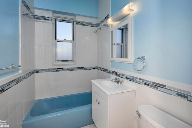 full bathroom with shower / washtub combination, tile walls, toilet, wainscoting, and vanity