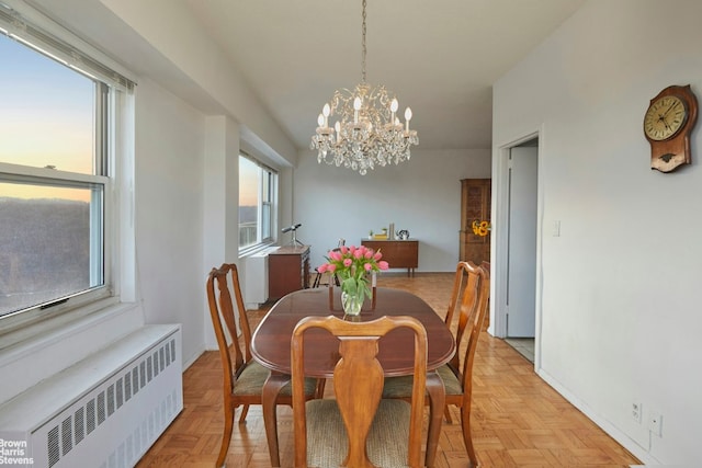 dining area featuring radiator heating unit, a wealth of natural light, and an inviting chandelier