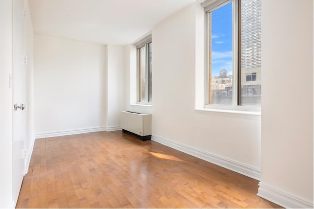 unfurnished room with baseboards, hardwood / wood-style floors, and radiator