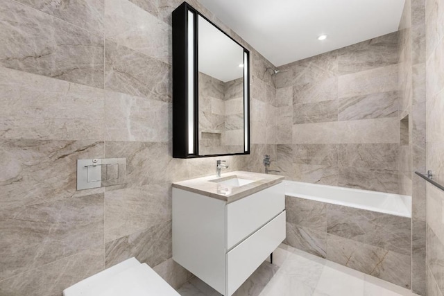 bathroom with tiled shower / bath, vanity, and tile walls