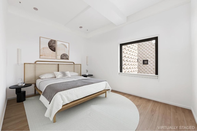 bedroom featuring beamed ceiling and light wood-type flooring