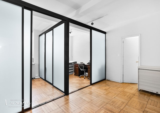 unfurnished bedroom featuring light parquet floors and rail lighting