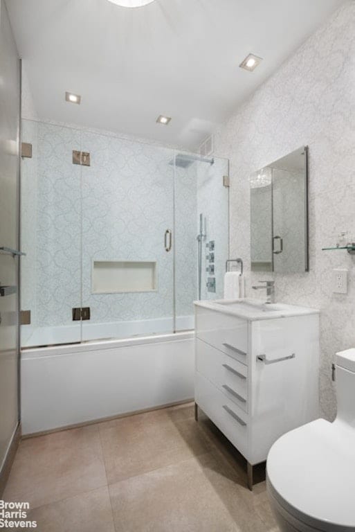 full bathroom featuring toilet, vanity, tile patterned flooring, and bath / shower combo with glass door