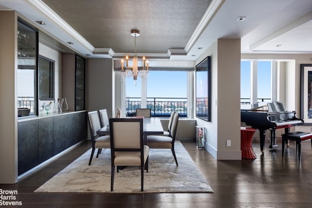 dining room with crown molding, dark hardwood / wood-style floors, a notable chandelier, and a raised ceiling