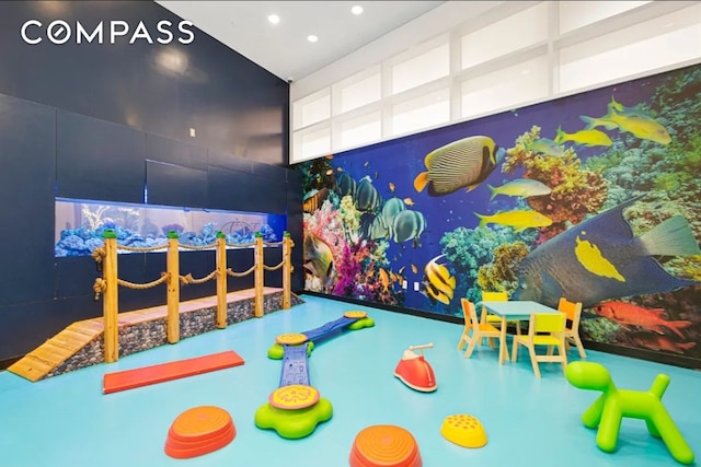 playroom with recessed lighting, finished concrete flooring, and a towering ceiling