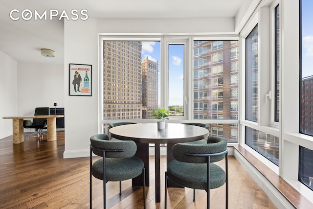 dining area with a view of city, baseboards, and wood finished floors