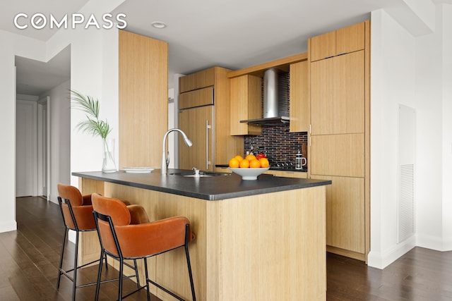 kitchen with paneled fridge, dark wood finished floors, a breakfast bar, dark countertops, and modern cabinets