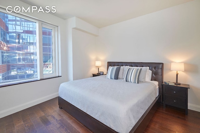 bedroom featuring multiple windows and dark hardwood / wood-style flooring