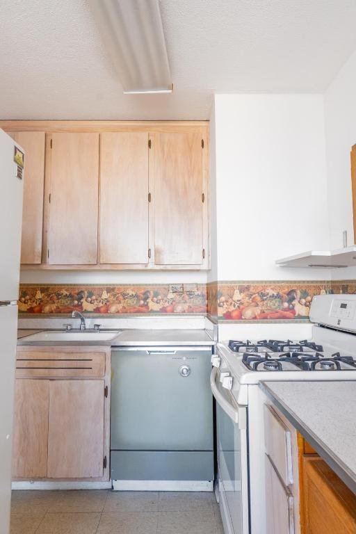 kitchen featuring light brown cabinetry, sink, white appliances, and light tile patterned flooring