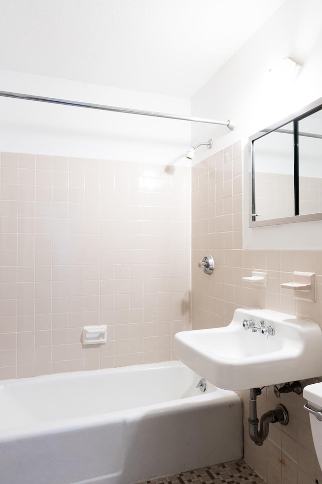 bathroom with tile walls, shower / bathtub combination, backsplash, toilet, and a sink