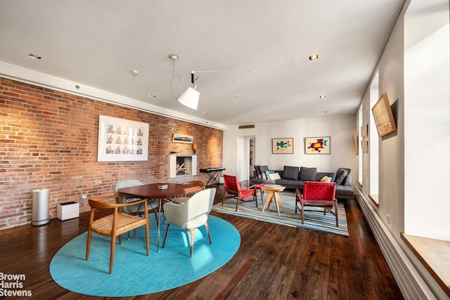 dining area featuring brick wall and dark wood-type flooring