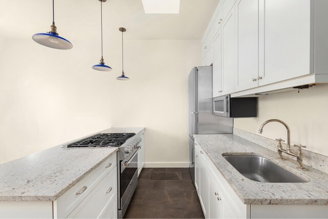 kitchen featuring stainless steel appliances, white cabinetry, sink, and decorative light fixtures