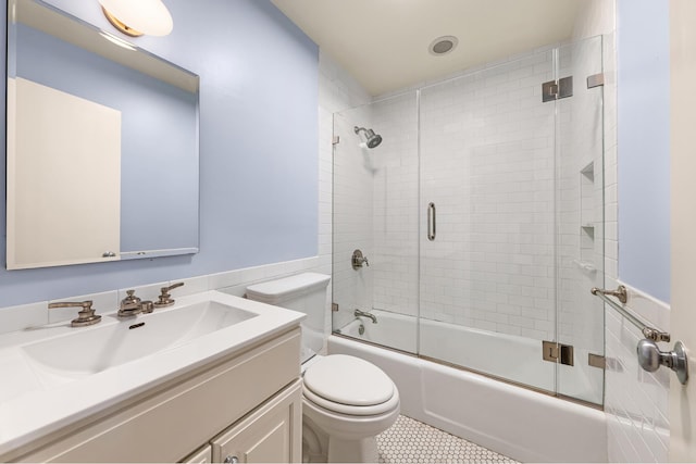 bathroom with enclosed tub / shower combo, toilet, tile patterned flooring, and vanity