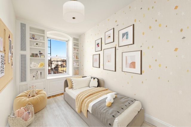 bedroom with light wood-type flooring, baseboards, and wallpapered walls