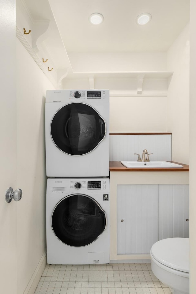 373 Bleecker St Unit Ph5Ad, New York City, NY 10014 - laundry area with stacked washing machine and dryer and light tile patterned floors